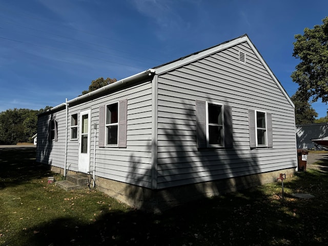 view of side of property with entry steps and a lawn