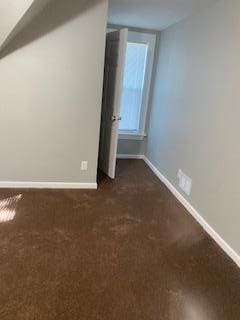 additional living space with dark colored carpet