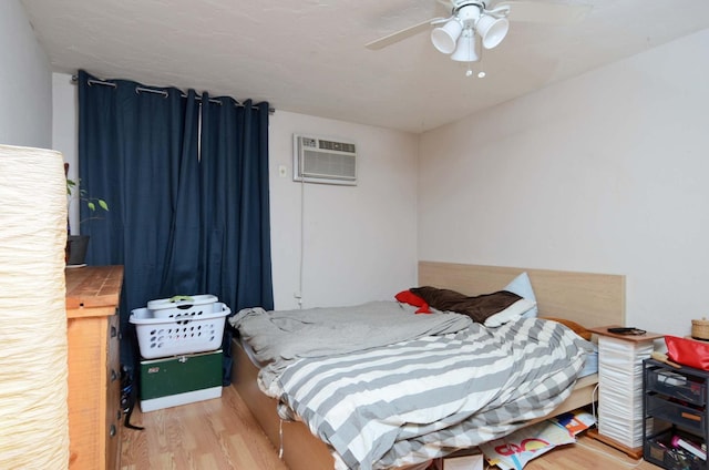 bedroom featuring light wood-type flooring, an AC wall unit, and ceiling fan