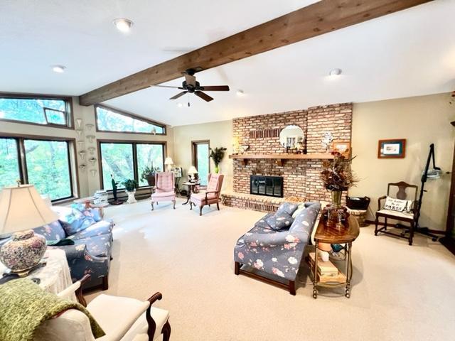 living room featuring vaulted ceiling with beams, light colored carpet, and a fireplace