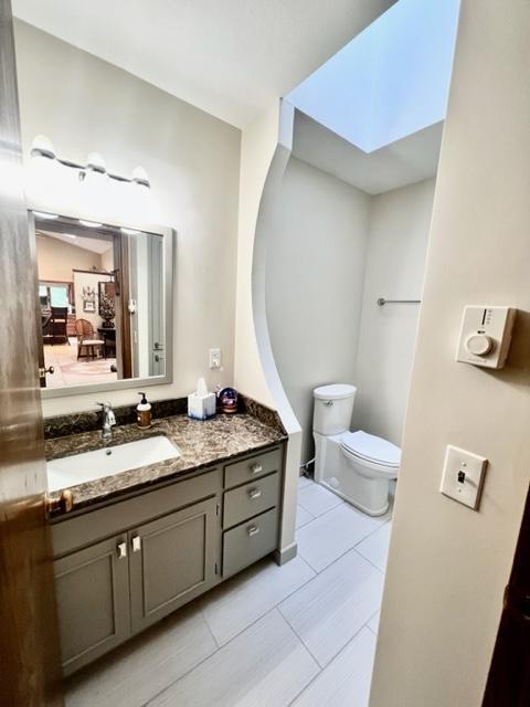 bathroom featuring tile patterned floors, a skylight, vanity, and toilet