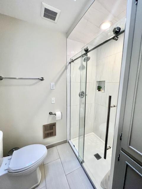 bathroom with tile patterned flooring, a shower with door, and toilet