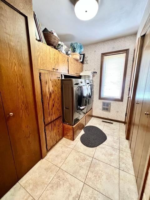 laundry room with cabinets, light tile patterned floors, and washer and dryer