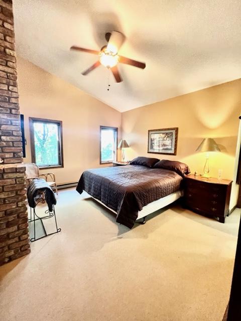 bedroom featuring vaulted ceiling, ceiling fan, carpet flooring, and a textured ceiling