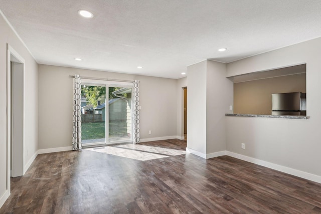 empty room with a textured ceiling and dark hardwood / wood-style floors