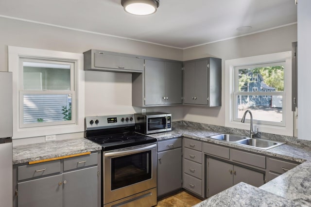 kitchen with appliances with stainless steel finishes, gray cabinetry, and sink