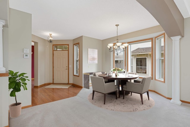 carpeted dining area featuring a chandelier and ornate columns