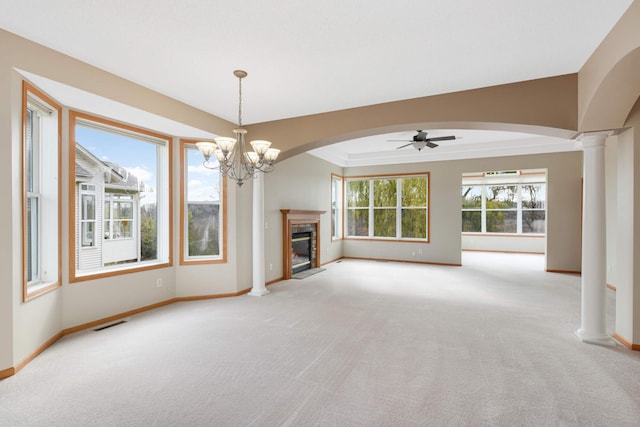 unfurnished living room featuring ceiling fan with notable chandelier, light colored carpet, and ornate columns