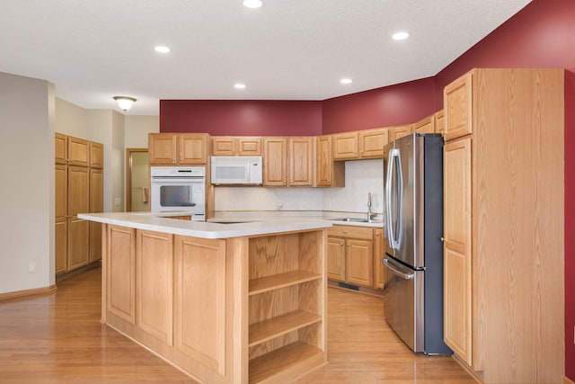 kitchen featuring stainless steel refrigerator, sink, a kitchen island, and light wood-type flooring