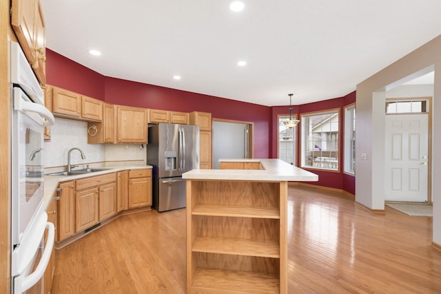 kitchen with sink, hanging light fixtures, a kitchen island, light hardwood / wood-style floors, and stainless steel fridge with ice dispenser