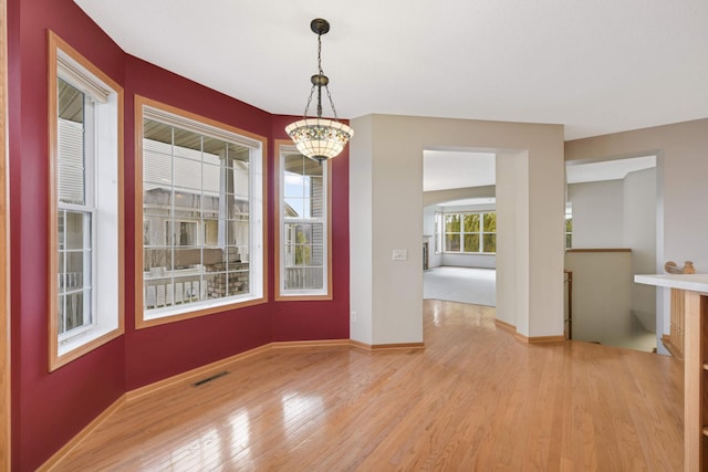 unfurnished dining area with light hardwood / wood-style floors and an inviting chandelier