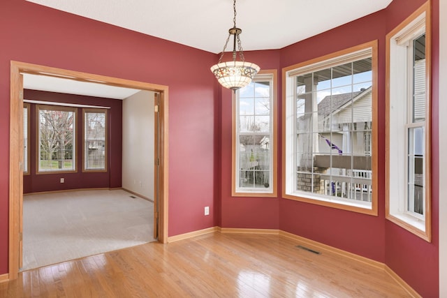 unfurnished dining area with light hardwood / wood-style flooring and an inviting chandelier