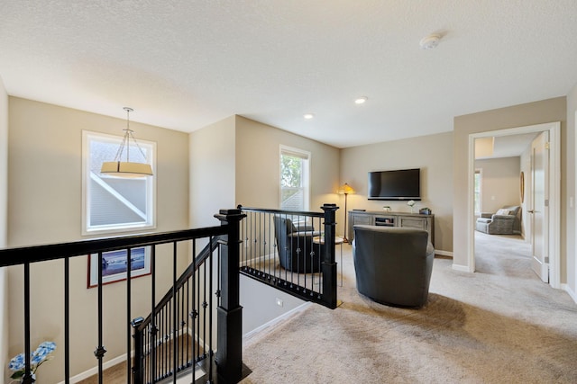 hall with a textured ceiling and light colored carpet