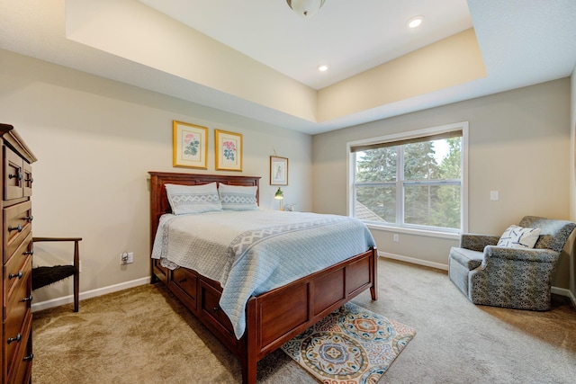 bedroom featuring a tray ceiling and light carpet