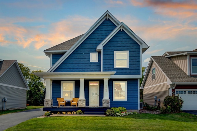 craftsman-style home with covered porch, a yard, and a garage