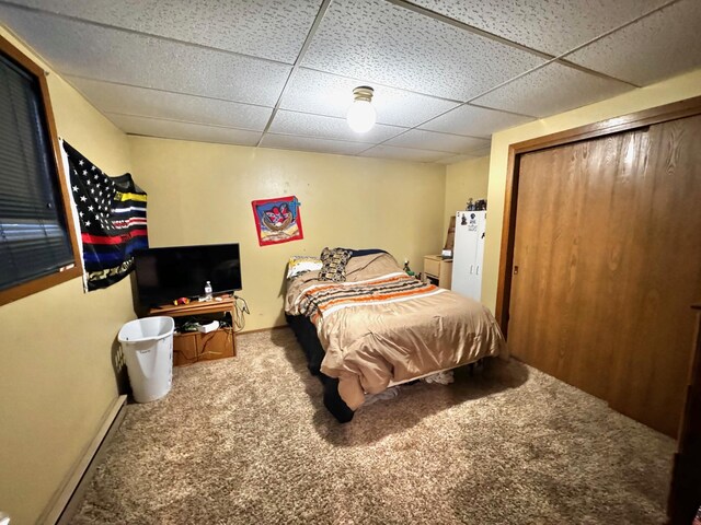 carpeted bedroom featuring a closet, a baseboard radiator, and a drop ceiling