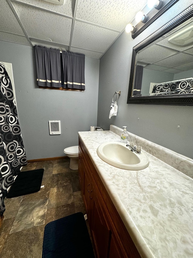 bathroom with vanity, toilet, and a drop ceiling