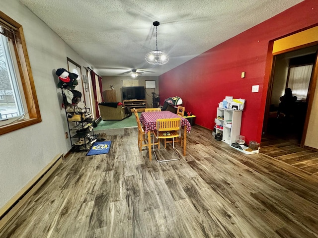 dining area featuring a textured ceiling, hardwood / wood-style flooring, a baseboard radiator, and ceiling fan