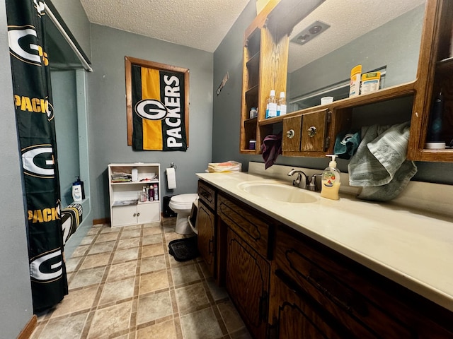 bathroom featuring vanity, toilet, and a textured ceiling