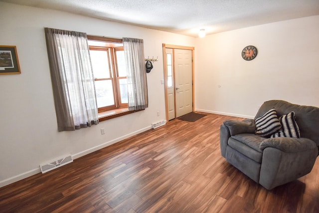 living area featuring a textured ceiling and dark hardwood / wood-style floors