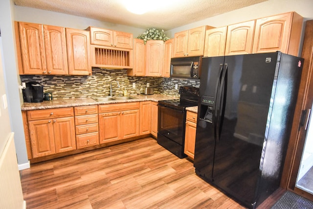 kitchen with sink, tasteful backsplash, black appliances, light stone countertops, and light hardwood / wood-style floors