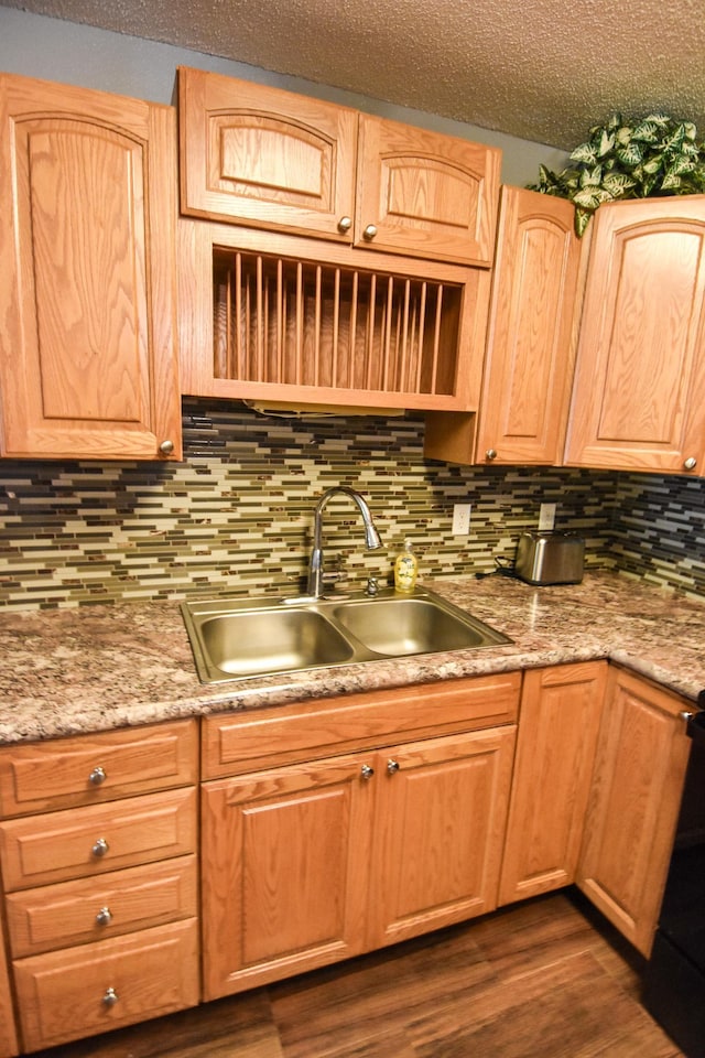 kitchen featuring black range oven, dark wood-type flooring, backsplash, a textured ceiling, and sink