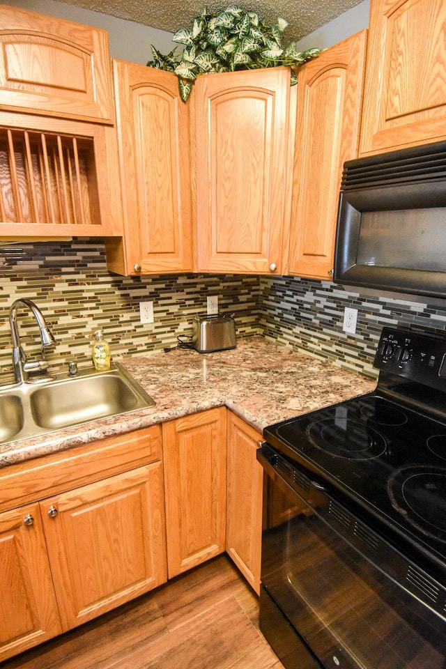 kitchen with a textured ceiling, black appliances, light wood-type flooring, and sink