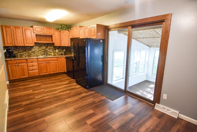 kitchen with black fridge, sink, tasteful backsplash, a textured ceiling, and dark hardwood / wood-style floors