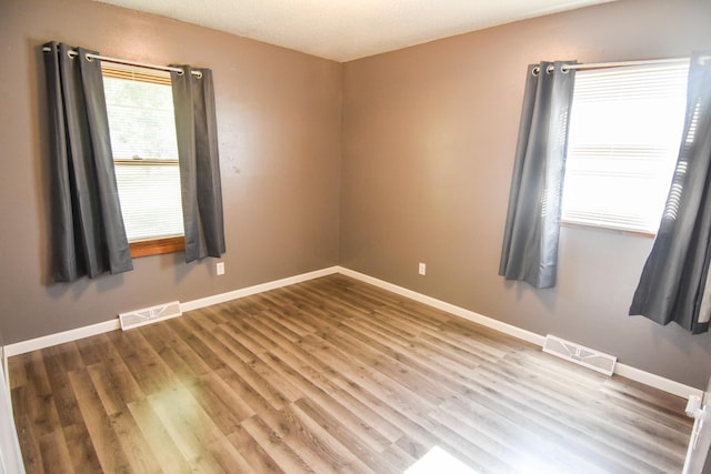 unfurnished room with hardwood / wood-style flooring and a textured ceiling