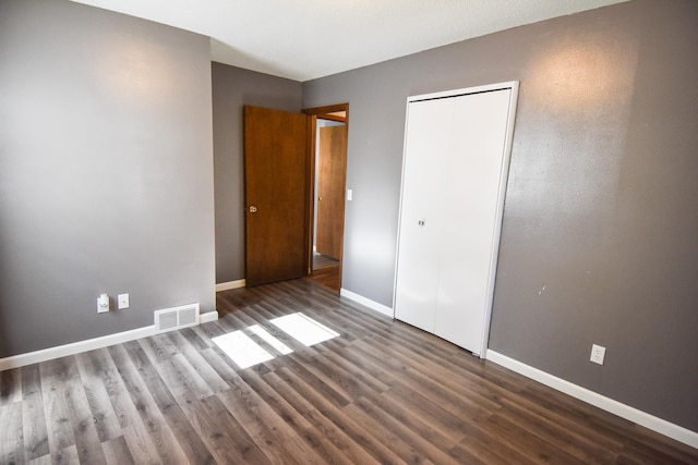 unfurnished bedroom with a closet and dark hardwood / wood-style floors