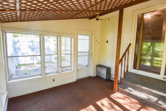 unfurnished living room featuring dark colored carpet and lofted ceiling