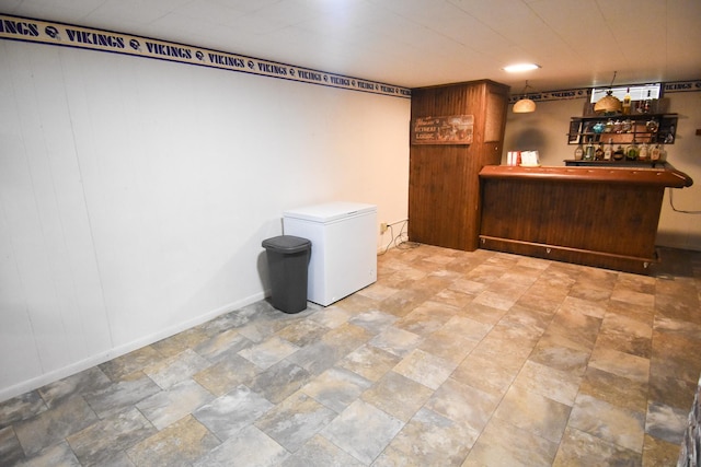 basement featuring fridge and indoor bar