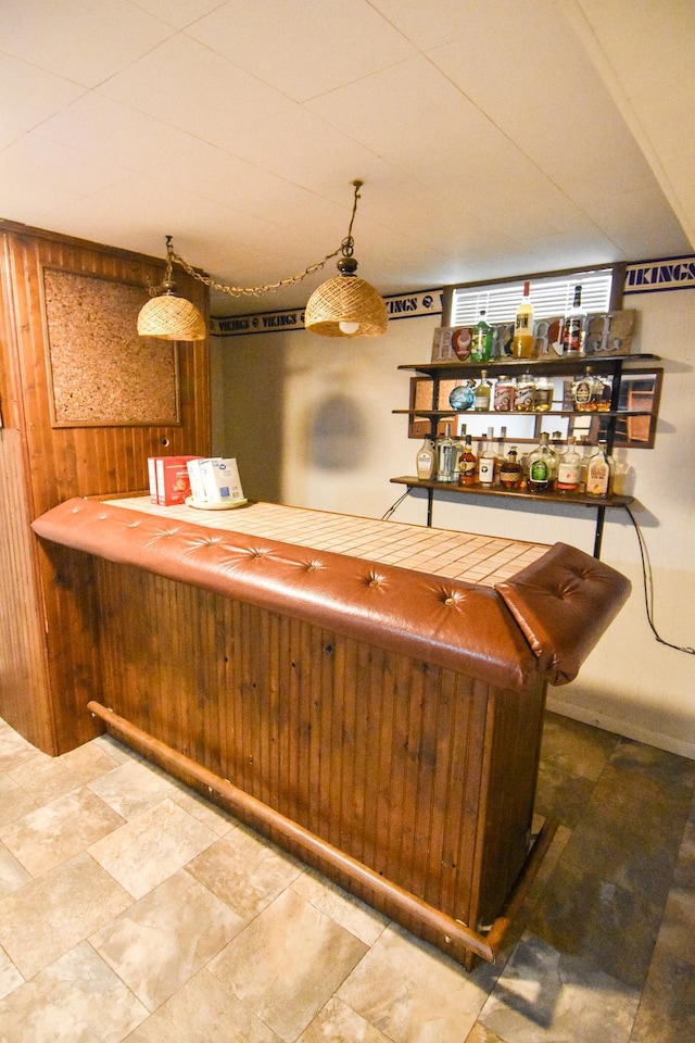 bar featuring wood walls and pendant lighting