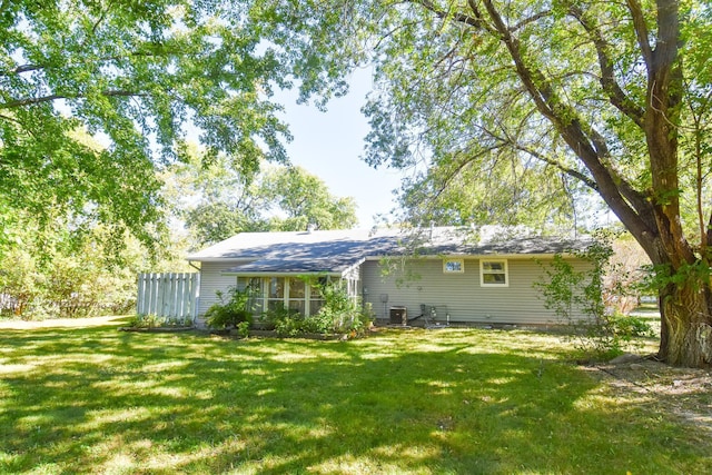 back of house featuring central AC unit and a lawn