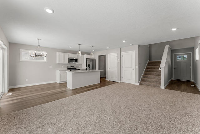 unfurnished living room featuring dark carpet, a textured ceiling, and a chandelier