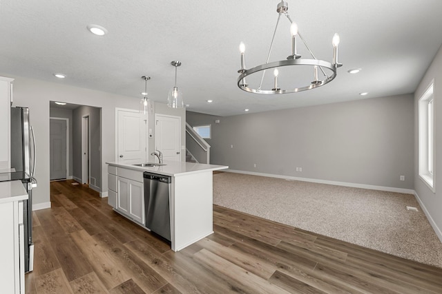 kitchen featuring appliances with stainless steel finishes, sink, pendant lighting, white cabinetry, and an island with sink