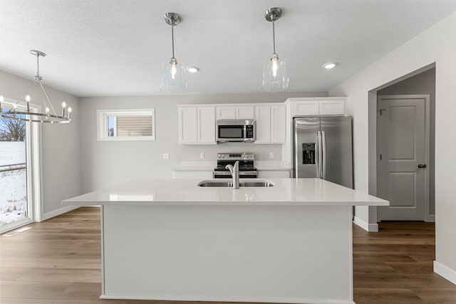 kitchen featuring white cabinets, pendant lighting, an island with sink, and appliances with stainless steel finishes