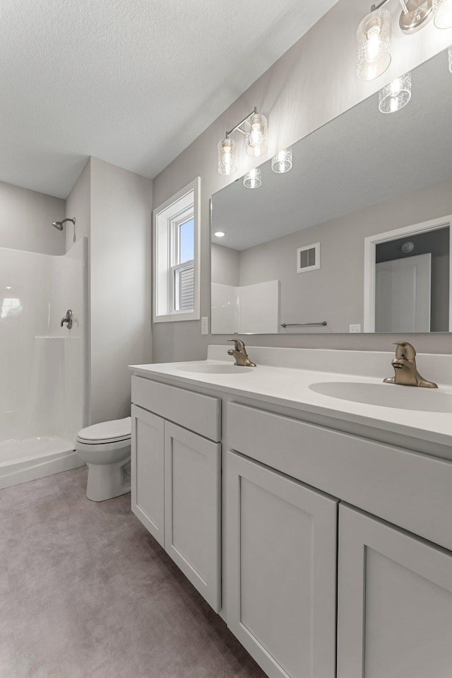 bathroom with a shower, vanity, a textured ceiling, and toilet