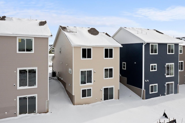 snow covered back of property with central AC