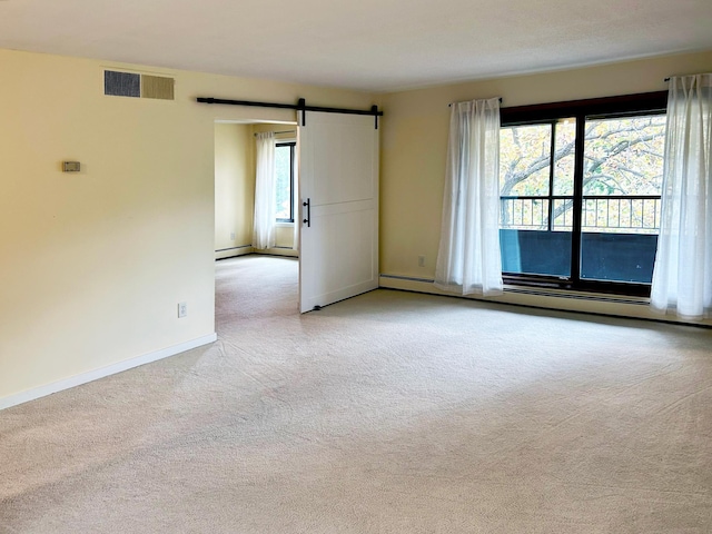 unfurnished room featuring a barn door, light colored carpet, baseboard heating, and plenty of natural light