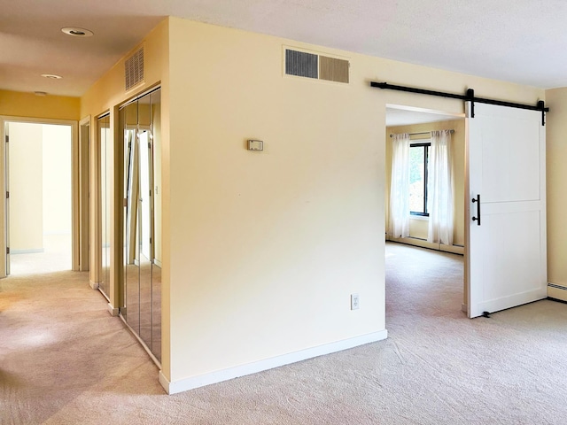 corridor featuring a barn door, light colored carpet, and baseboard heating