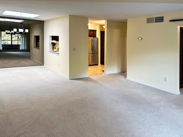 carpeted empty room featuring a skylight and a notable chandelier