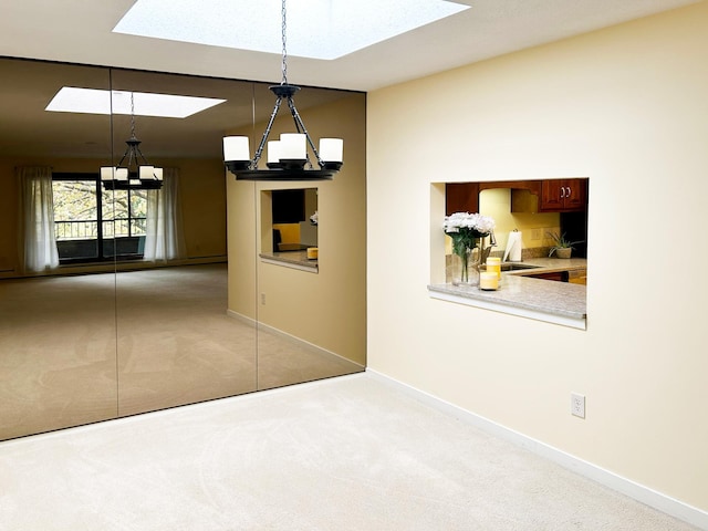 carpeted spare room with a skylight and an inviting chandelier