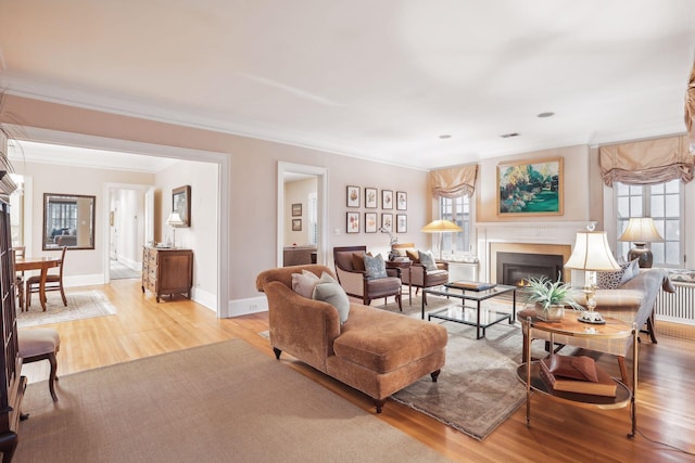 living room featuring crown molding, light hardwood / wood-style floors, and a wealth of natural light