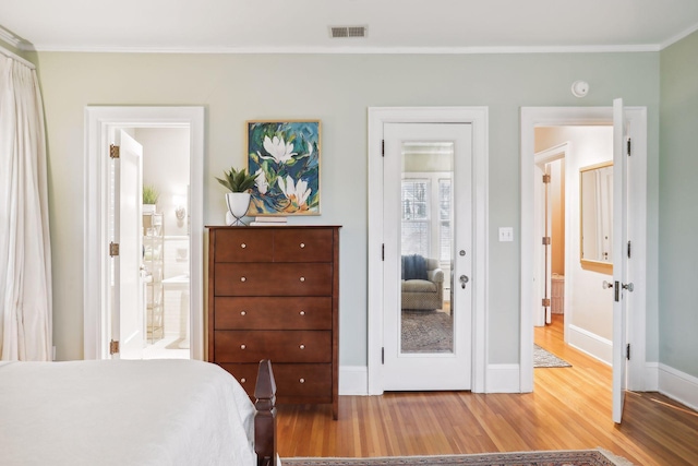 bedroom featuring ornamental molding, hardwood / wood-style flooring, and ensuite bathroom