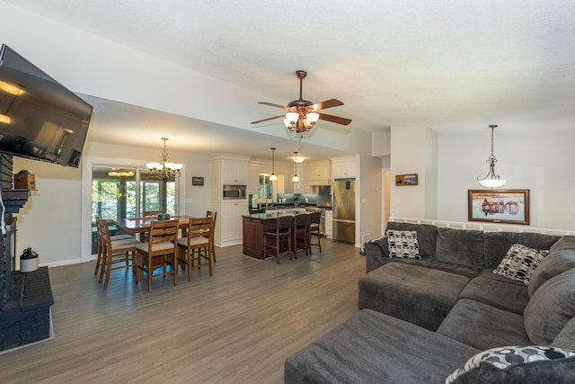 living room with ceiling fan with notable chandelier and dark hardwood / wood-style floors