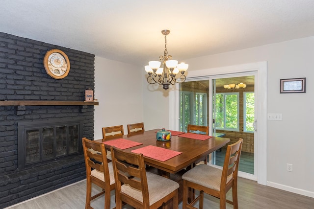 dining space with a fireplace, a chandelier, and hardwood / wood-style floors