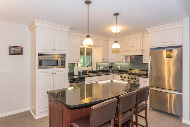 kitchen with light wood-type flooring, a center island, sink, white cabinetry, and appliances with stainless steel finishes