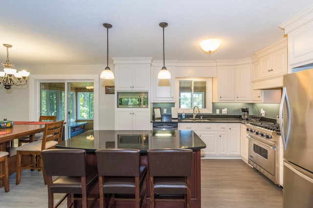 kitchen featuring white cabinets, sink, stainless steel appliances, and decorative light fixtures