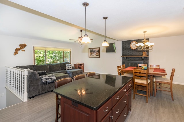 kitchen featuring pendant lighting, a brick fireplace, dark brown cabinets, and light wood-type flooring